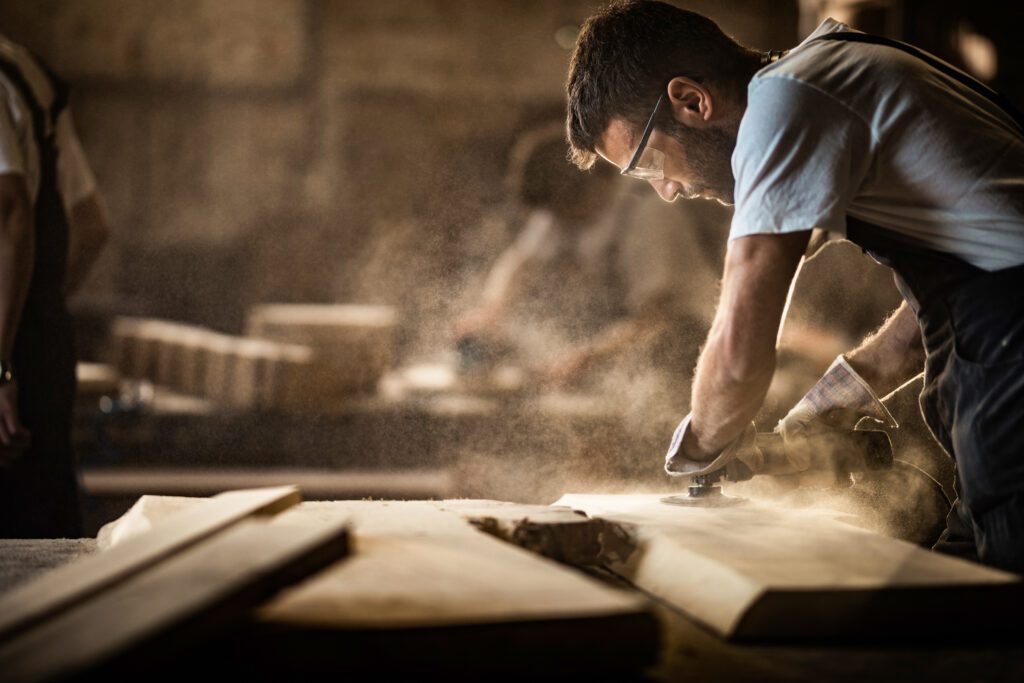 Young carpenter using sander while working on a piece of wood.